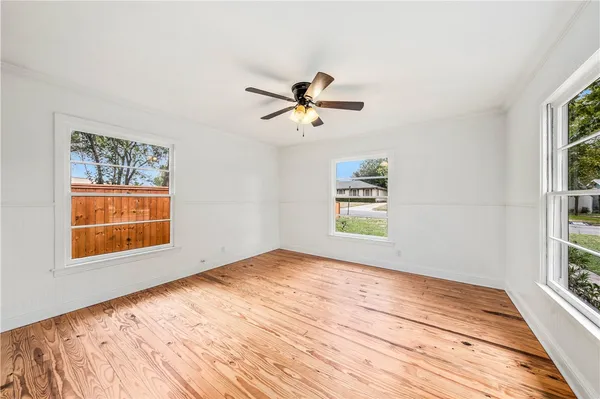 a view of empty room with wooden floor and fan