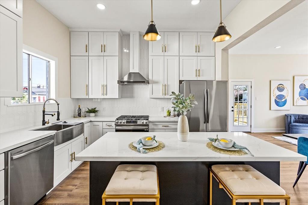 a kitchen with stainless steel appliances granite countertop a sink dishwasher a stove a refrigerator a microwave oven with white cabinets and wooden floor