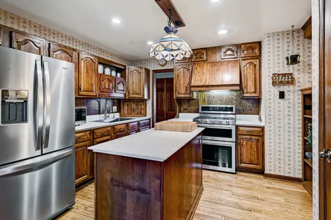 a kitchen with stainless steel appliances granite countertop a refrigerator a stove and a sink with wooden floor