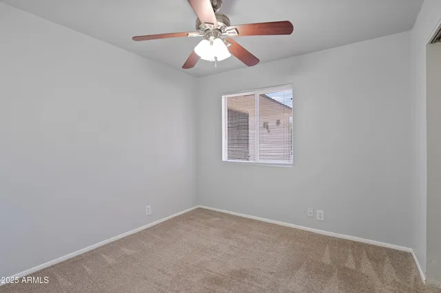 an empty room with a window and a fan