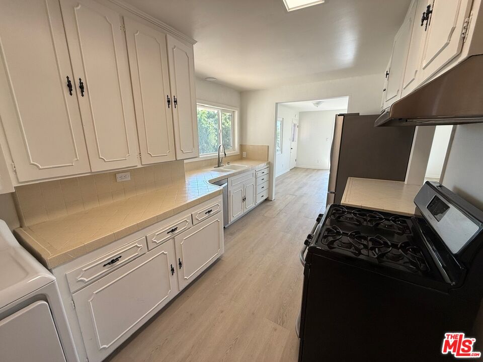 3237 Midvale Avenue Los Angeles, CA 90034 - Photo 7 of 24 a kitchen with granite countertop white cabinets and black appliances