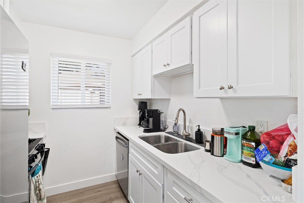 1723 Normandy Place, Unit D Santa Ana, CA 92705 - Photo 3 of 18 a kitchen with stainless steel appliances granite countertop a sink dishwasher and white cabinets with wooden floor