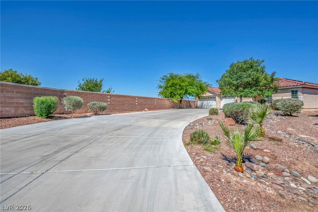 6405 North Raptor Court North Las Vegas, NV 89084 - Photo 3 of 66 A long paved driveway leads to the residence, complemented by desert landscaping and a sturdy brick fence.