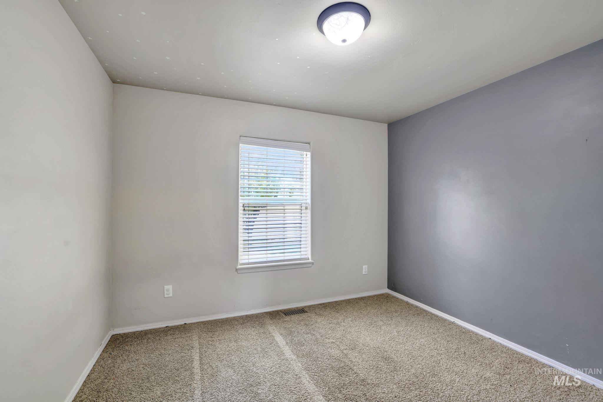 446 Noble Street Twin Falls, ID 83301 - Photo 12 of 42 Carpeted room with a central window, white blinds, and two-tone wall paint