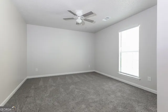 an empty room with a window and a ceiling fan