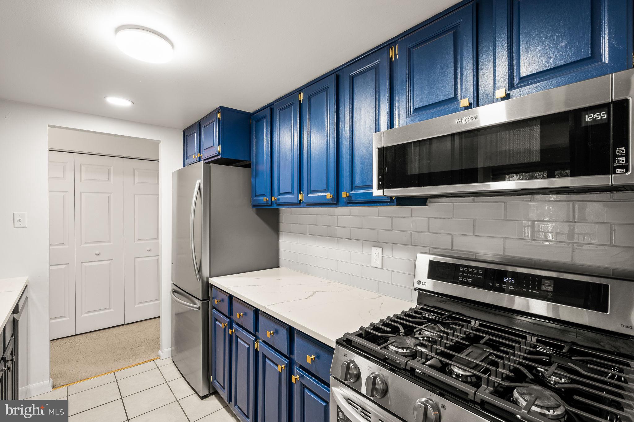 288 Drummers Lane, Unit 288 Wayne, PA 19087 - Photo 5 of 30 a kitchen with stainless steel appliances kitchen island granite countertop wooden cabinets and a stove top oven