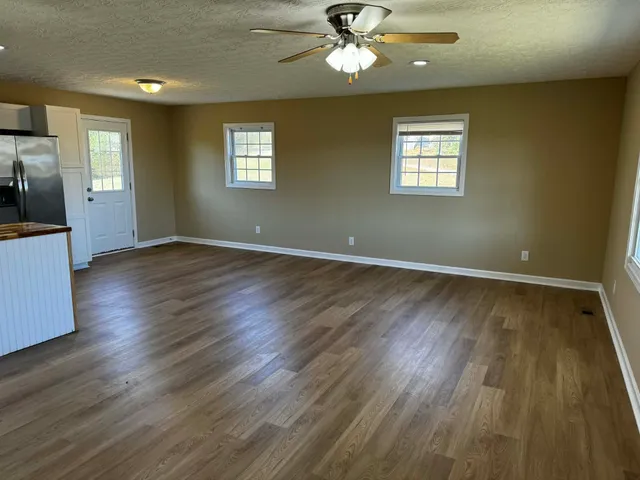 a view of an empty room with a window and wooden floor