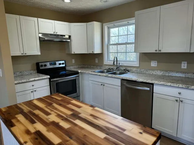 a kitchen with stainless steel appliances granite countertop a sink stove and cabinets