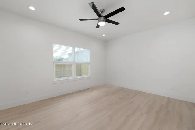 an empty room with a window and a fan