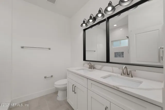 a bathroom with a granite countertop sink a toilet and mirror