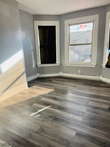 a view of an empty room with wooden floor and window
