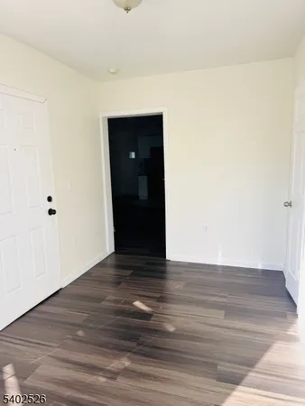 a view of an empty room with wooden floor and closet