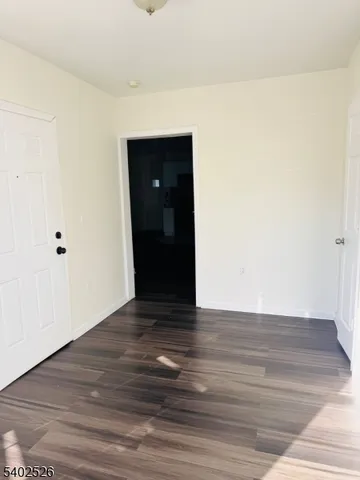 a view of an empty room with wooden floor and closet
