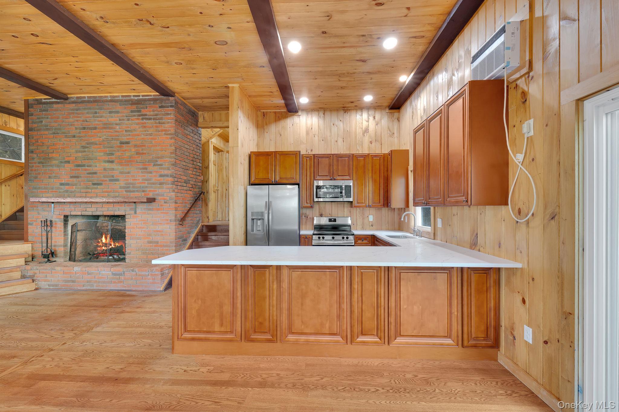 53 West Corbett Road Montgomery, NY 12549 - Photo 7 of 41 Kitchen with a wooden ceiling with exposed beams, a peninsula, recessed lighting, wood walls, and stainless steel appliances Level 3