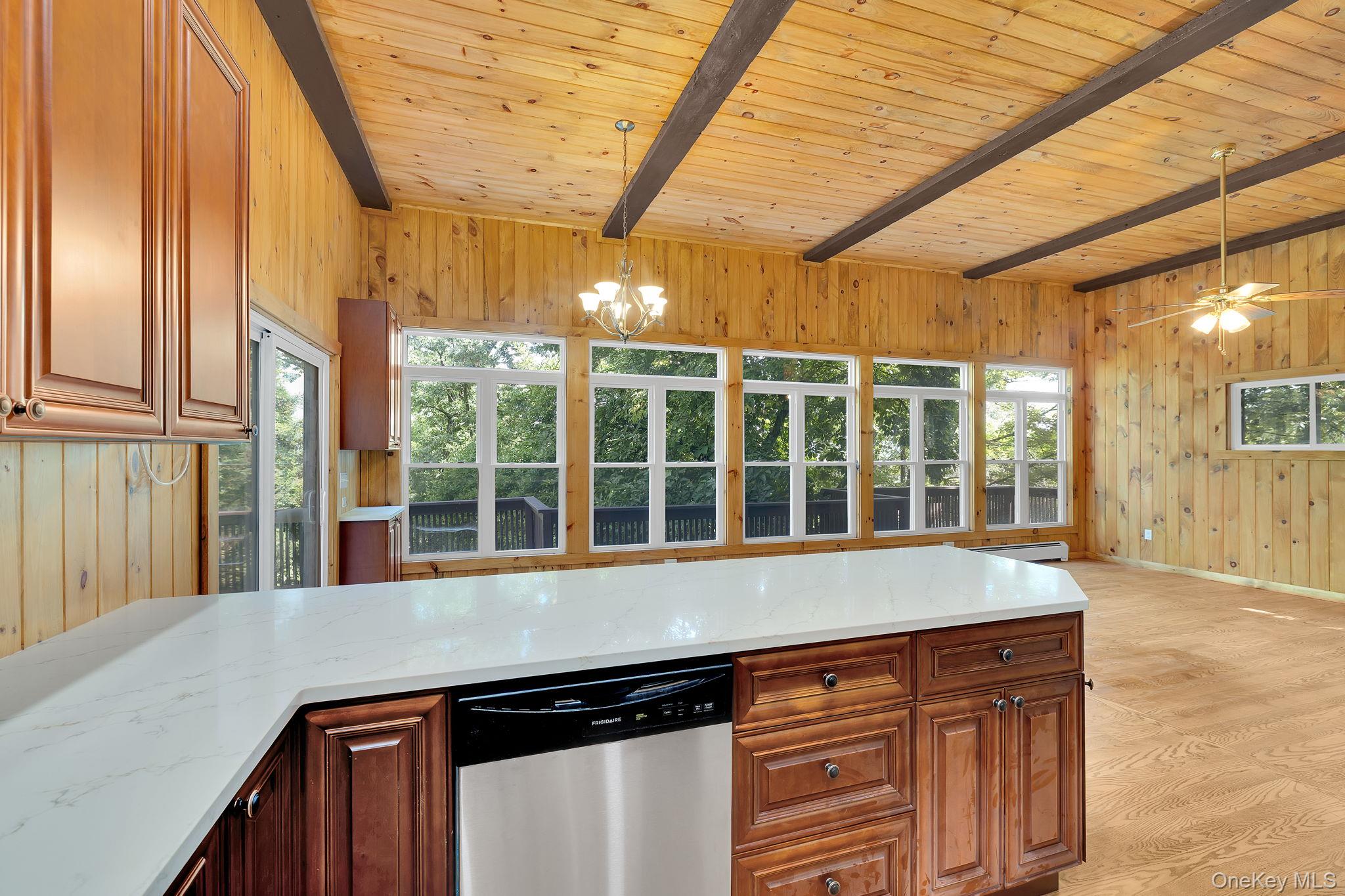 53 West Corbett Road Montgomery, NY 12549 - Photo 8 of 41 Kitchen with wood walls, light stone countertops, stainless steel dishwasher, decorative light fixtures, and light wood finished floors Level 3