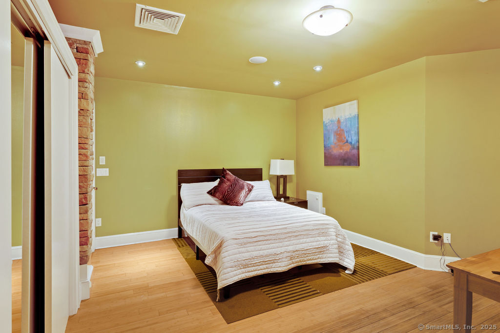 76 Sachem Head Road Guilford, CT 06437 - Photo 23 of 40 a bedroom with a bed and wooden floor