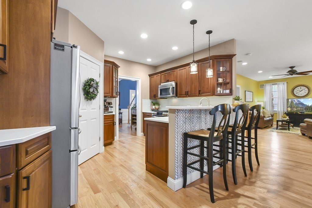 40 Oheir Way Lowell, MA 01852 - Photo 7 of 42 a kitchen with stainless steel appliances granite countertop a refrigerator a stove top oven and a dining table with wooden floor