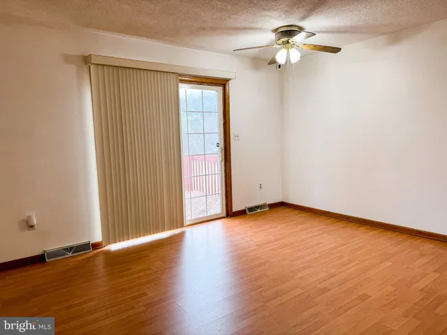 an empty room with wooden floor fan and windows
