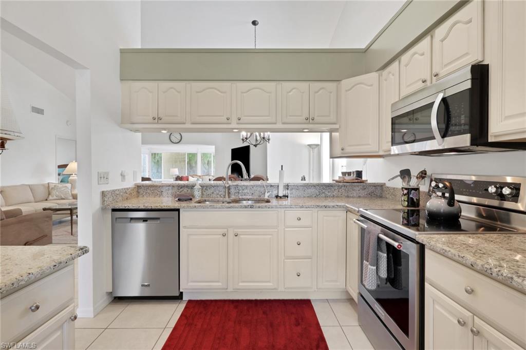841 Kings Way Naples, FL 34104 - Photo 43 of 43 Kitchen with appliances with stainless steel finishes, light tile patterned flooring, light stone counters, open floor plan, and white cabinets