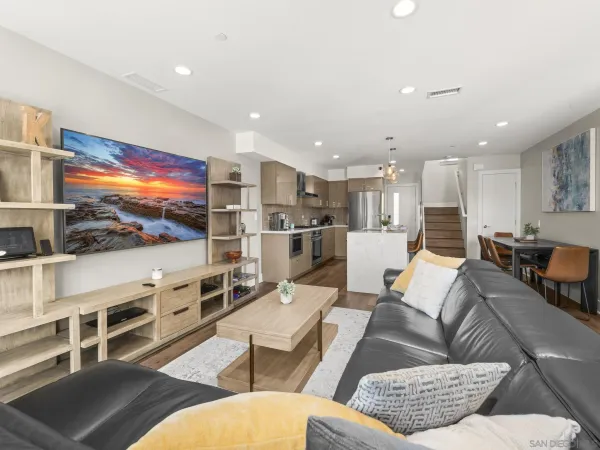 a living room with furniture kitchen view and a flat screen tv