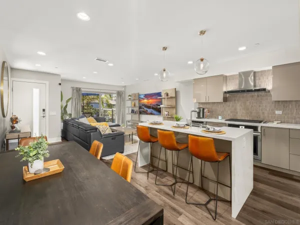a kitchen with stainless steel appliances granite countertop a refrigerator a sink dishwasher a dining table and chairs with wooden floor