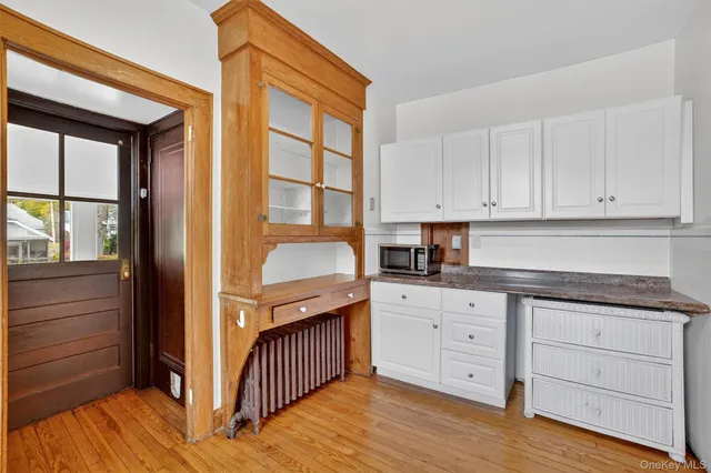 a kitchen with granite countertop white cabinets and wooden floor