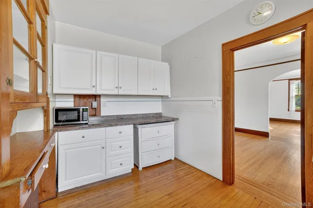 a kitchen with granite countertop white cabinets and wooden floor