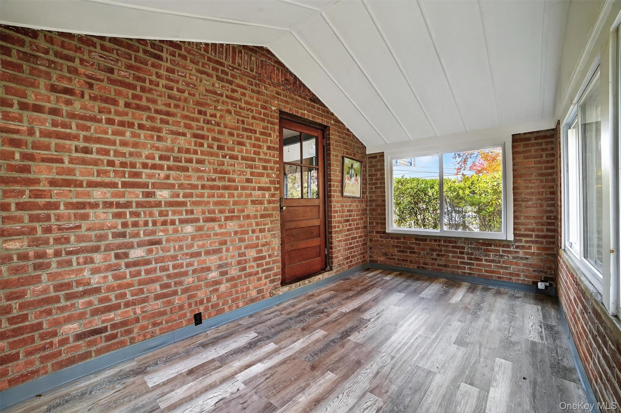 64 Elmore Avenue Croton-on-Hudson, NY 10520 - Photo 27 of 36 Unfurnished sunroom with vaulted ceiling, brick wall, and wood finished floors