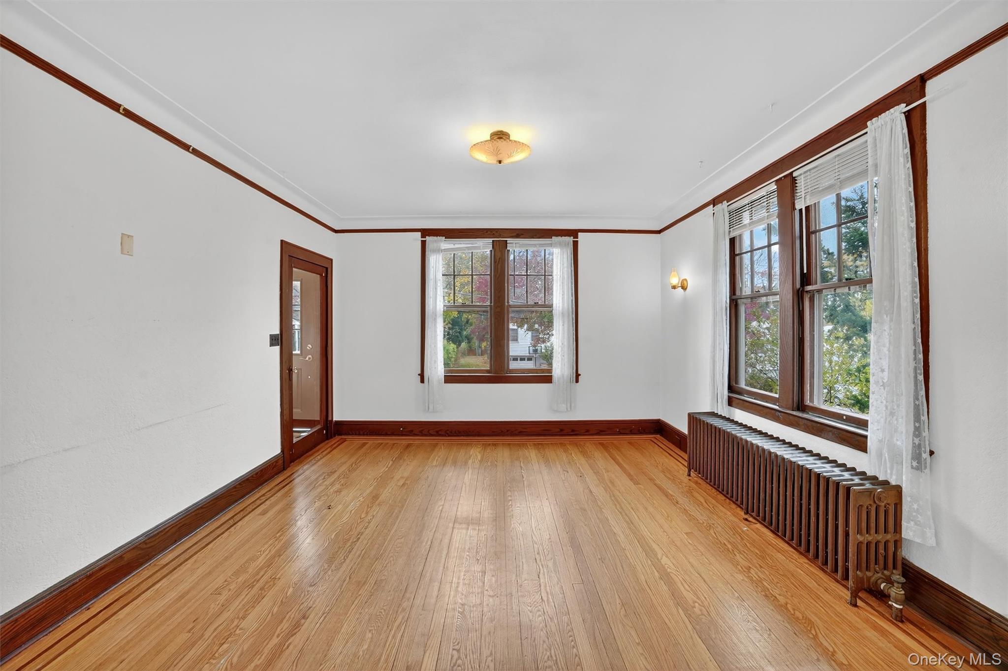 64 Elmore Avenue Croton-on-Hudson, NY 10520 - Photo 4 of 36 Unfurnished room with radiator heating unit, crown molding, healthy amount of natural light, and light wood-type flooring
