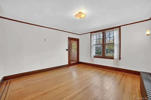 a view of an empty room with window and wooden floor