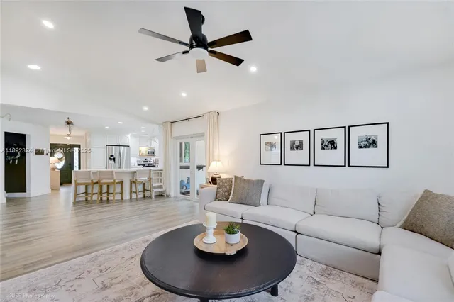 a living room with furniture kitchen view and a wooden floor