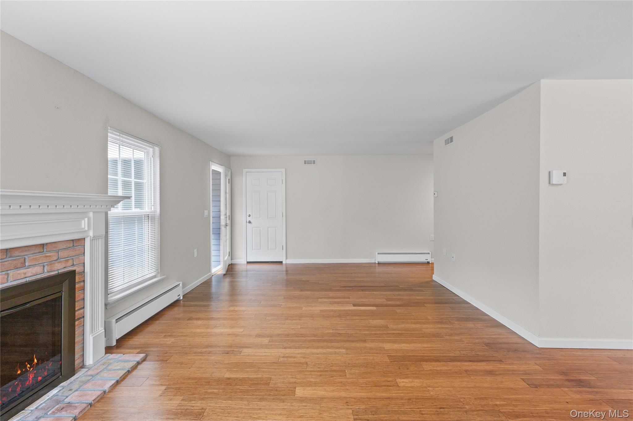 220 Belfast Lane Ridge, NY 11961 - Photo 11 of 44 a view of an empty room with wooden floor fireplace and a window
