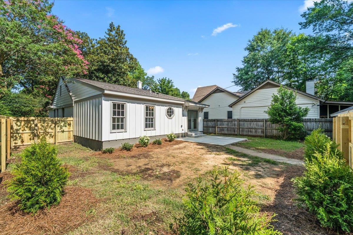 170 South Greer Street Memphis, TN 38111 - Photo 31 of 35 Rear exterior of a white board-and-batten structure featuring multiple windows, a circular window, and a concrete patio
