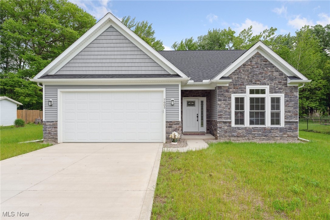 7605 Lake Road East Madison, OH 44057 - Photo 1 of 50 Craftsman-style house featuring stone siding, concrete driveway, an attached garage, and roof with shingles