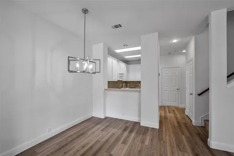 a view of a room with wooden floor and kitchen view