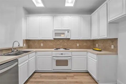 a kitchen with white cabinets appliances and a sink