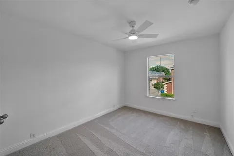 an empty room with window and ceiling fan