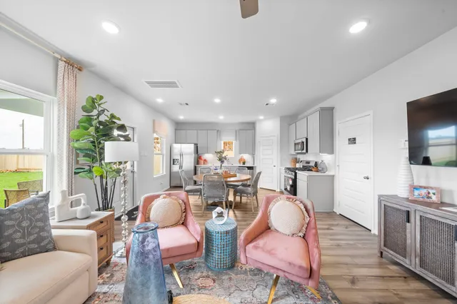 a living room with furniture kitchen view and a large window