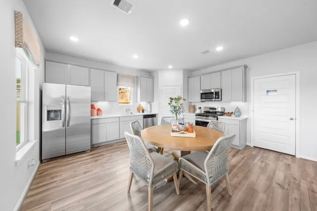 a kitchen with a refrigerator a dining table and chairs