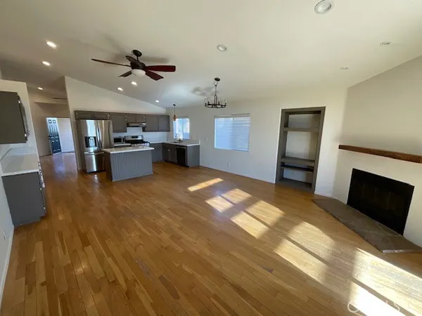 a large living room with stainless steel appliances kitchen island granite countertop a fireplace and a view of kitchen