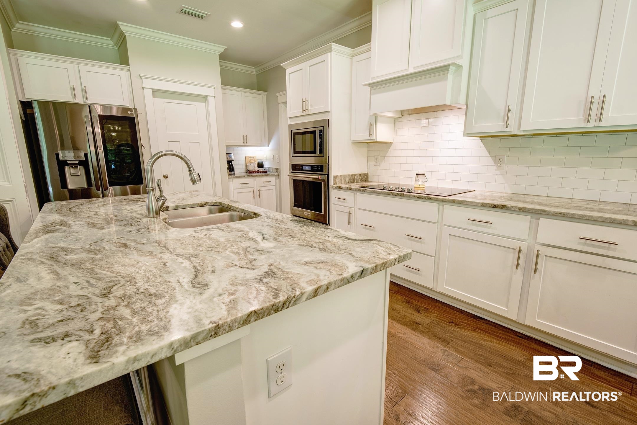 18754 Treasure Oaks Road Gulf Shores, AL 36542 - Photo 31 of 53 Kitchen featuring a large central island with a double basin sink, stainless steel faucet, and stone countertop