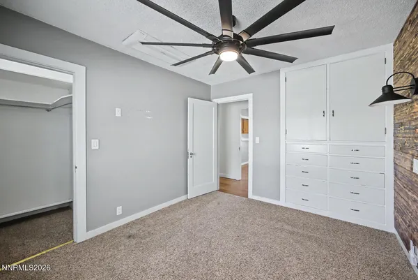 an empty room with wooden floor chandelier fan and windows