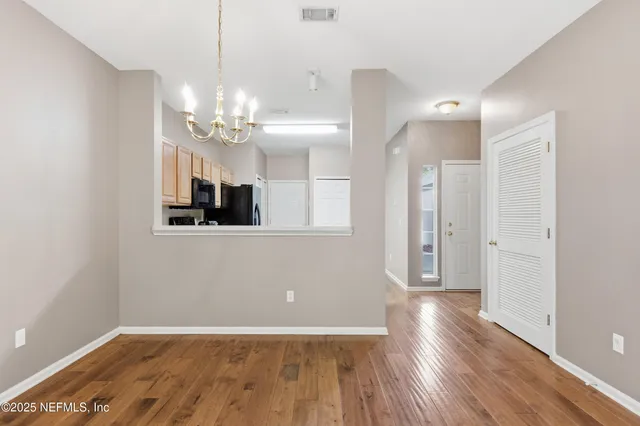 a view of a livingroom with a chandelier fan and wooden floor