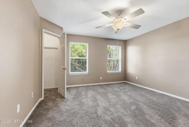 an empty room with windows and ceiling fan