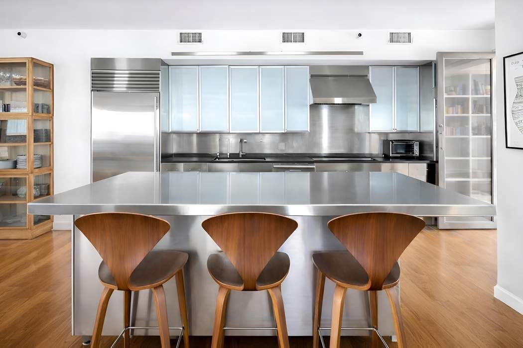 145 6th Avenue, Unit 5D Manhattan, NY 10013 - Photo 3 of 9 a kitchen with a table chairs cabinets and wooden floor