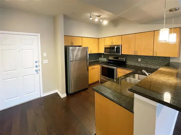 a kitchen with kitchen island granite countertop a sink appliances and cabinets