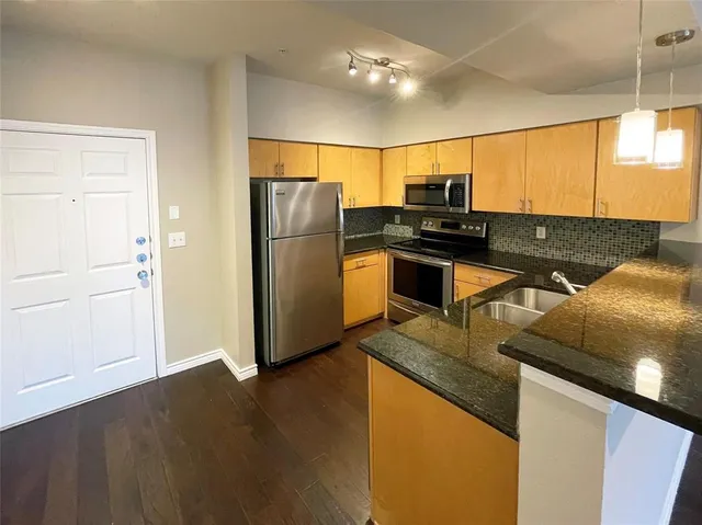 a kitchen with kitchen island granite countertop a sink appliances and cabinets