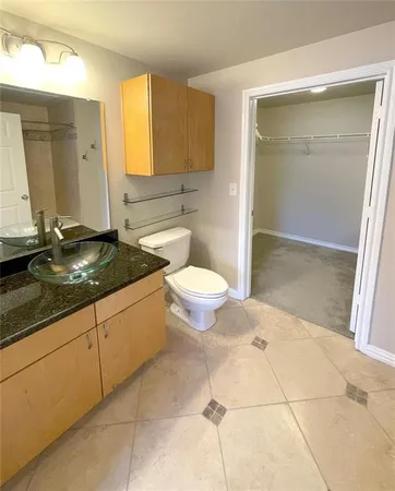 a bathroom with a granite countertop sink a toilet and a mirror