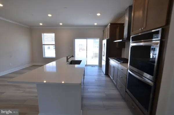 a open kitchen with stainless steel appliances kitchen island granite countertop a refrigerator a stove and a sink with wooden floor