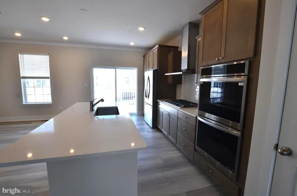 a large kitchen with stainless steel appliances a large counter top a stove and a refrigerator